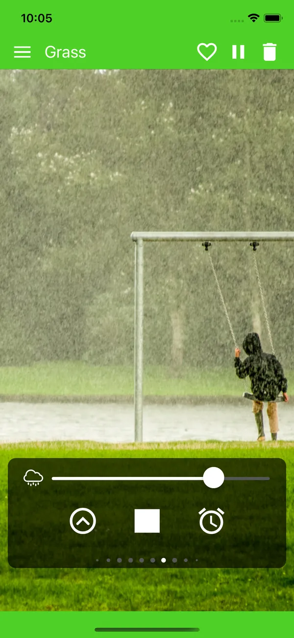 Rain falling on grass behind a child on a swing